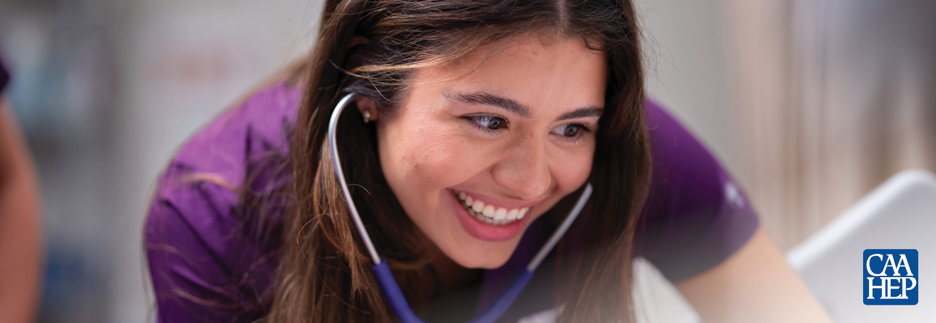 Close-up of a student in Mercy Health Sciences University scrubs listening with a stethoscope while practicing clinical assessment skills in a simulated healthcare setting.